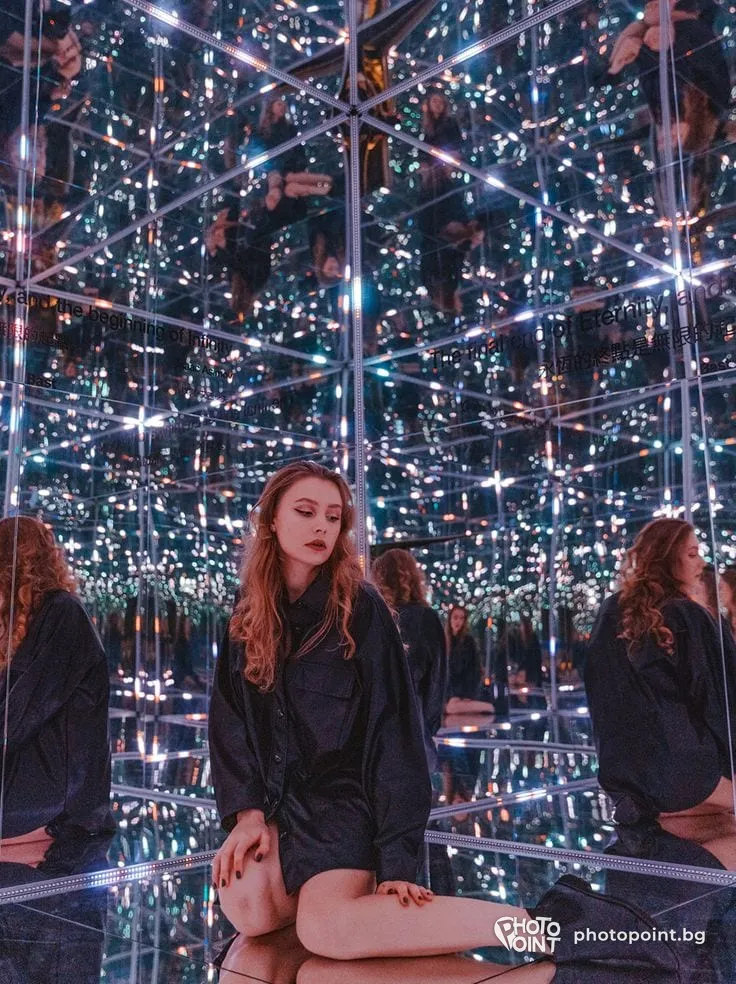 A girl sitting among the endless reflections in the mirror room